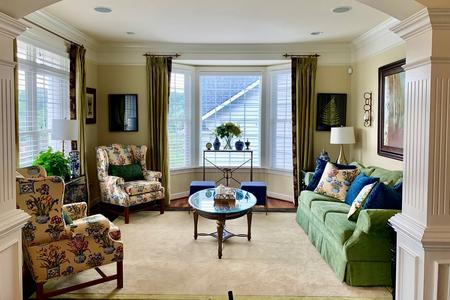 Floral wing chairs and a green sofa in a finished living room